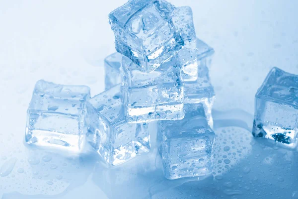 Cubos de hielo cuadrados con gotas de agua limpia sobre fondo azul —  Fotos de Stock