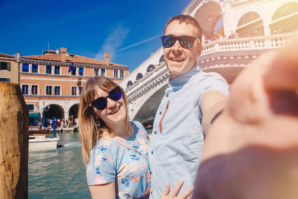 Selfie älskare par tar foto resor Venedig, Italien mot bakgrund av stor kanal och bro — Stockfoto