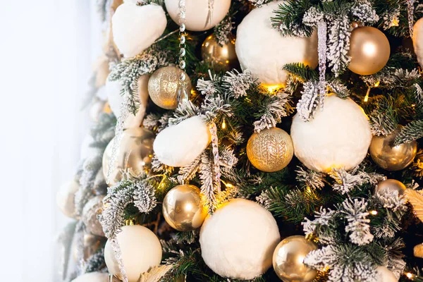 Christmas background in light and gold tones, New Year tree decorated with balls and artificial snow illumination — Stock Photo, Image