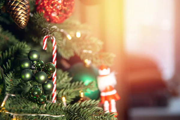 Boże Narodzenie tło drzewo gałąź z dekoracje cukierki lizak trzcina czerwony i zielony kulki, z bokeh słońce światło — Zdjęcie stockowe
