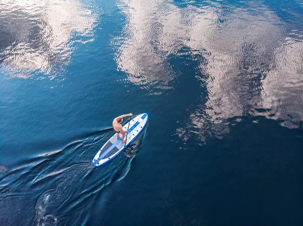 Man rodd åra på sup ombord blått havsvatten. Aerial ovanifrån paddelbräda — Stockfoto