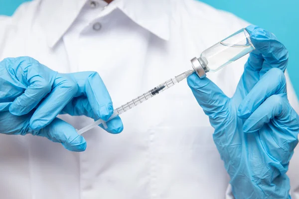 Доктор рука тримає шприц і вакцину в синіх рукавичках біле пальто. Концепція ін'єкцій хвороби — стокове фото