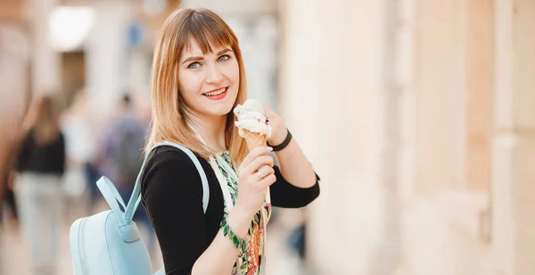 Belle fille touristique tient et mange de la crème glacée italienne dans le cône et regarde dans le cadre — Photo