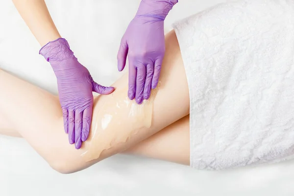 Proses depilasi kaki gadis dengan pasta gula di spa salon, latar belakang putih. Konsep hair removal Shugaring. Tampilan atas — Stok Foto