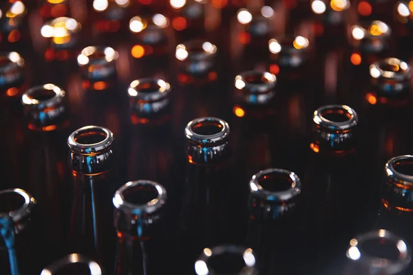 Glass bottles of beer on dark background. Concept brewery plant production line