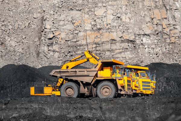 Большой желтый грузовик с грузом антрацита перемещает шахту по добыче угля
