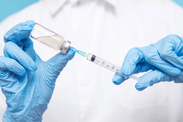 Lékařská ruka držící injekční stříkačku a vakcínu v modrých rukavicích. Koncepce injekce onemocnění — Stock fotografie