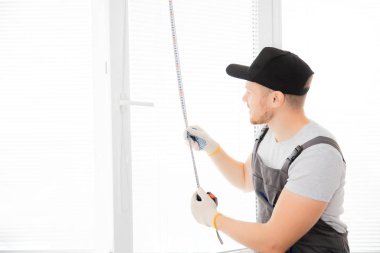 Usta işçi üst pencereyi cetvel ve kurulum süreci ile ölçer