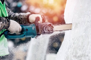 Buz heykeli oymacılığı yapan adam elektrikli testere kullanır. Donmuş kışı keser.