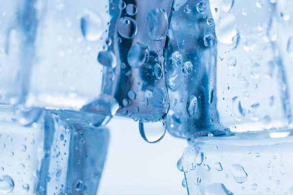 파란색 배경에 깨끗 한 물방울을 떨어뜨려 놓은 네모난 얼음 — 스톡 사진