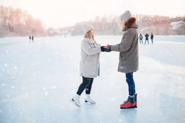 Uomo dando regalo scatola fidanzata inverno sulla pista di pattinaggio, sorpresa romantica per San Valentino o Natale. sfondo neve tramonto — Foto Stock