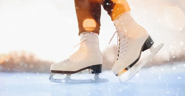 La chica está de pie sobre hielo en patines blancos, copos de nieve, luz solar. Concepto de vacaciones activas de invierno — Foto de Stock