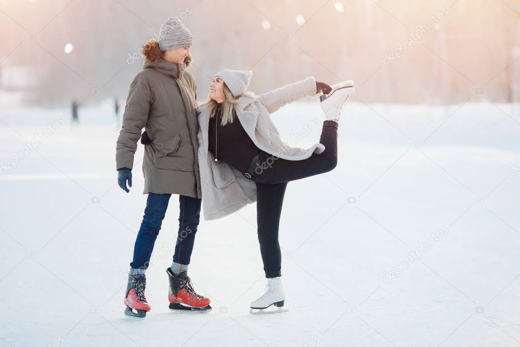 Winter skates, loving couple holding hands and rolling on rink. Concept training