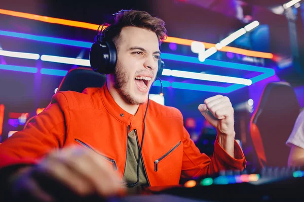 Streamer νεαρός άνδρας χαίρεται στη νίκη επαγγελματίας gamer παίζοντας online παιχνίδια υπολογιστή με ακουστικά, νέον χρώμα — Φωτογραφία Αρχείου
