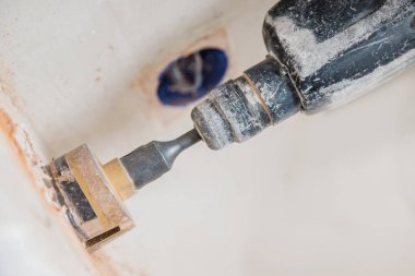 Pnömatik çekiç delici ve elmas kaplama delgisi olan tamirci elektrik kablosu, soket, anahtar için duvarda delik açıyor.