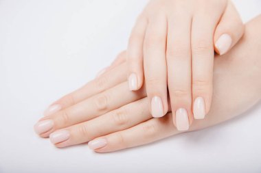 Modayı takip eden genç bir kadın beyaz arka planda pembe manikür yapıyor.