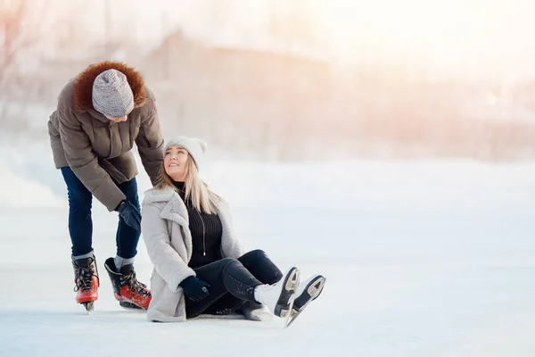 Chica muestra chico donde ella tiene dolor después de caída lesión en pista de patinaje sobre hielo en invierno — Foto de Stock