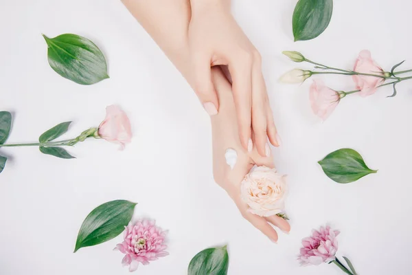 Kosmetikcreme auf weiblichen Händen mit rosa Blüten auf weißem Hintergrund, flache Lage. Konzept Wellness Winter Hautpflege — Stockfoto