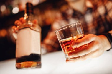 Barman erkek ziyaretçiye buzlu bir bardak viski tutuyor. Konsept dinlenme barda