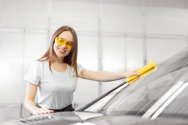 Sünger araba servisiyle ön camı yıkayan güzel bir kadın işçi. — Stok fotoğraf