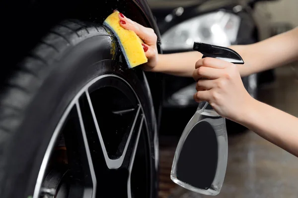 Araba yıkama servisi, siyah lastikleri silmek için sprey ve sünger kullanın. — Stok fotoğraf