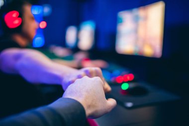 Profesyonel oyuncu selamlaması ve destek ekibi online oyunu neon rengi bulanık arka planda yumrukluyor. Yumuşak odak, arka görünüm