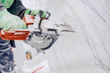 Buz heykeli oymacılığı yapan adam elektrikli testere kullanır. Donmuş kışı keser.