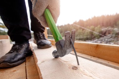 İnşaatçı ağaçtan çiviyi çekerek çıkarır.