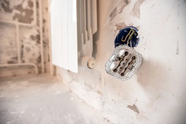 Rozmontowane gniazdko elektryczne w ścianie detonacyjnej z gołymi przewodami i znamionami podczas naprawy w mieszkaniu — Zdjęcie stockowe