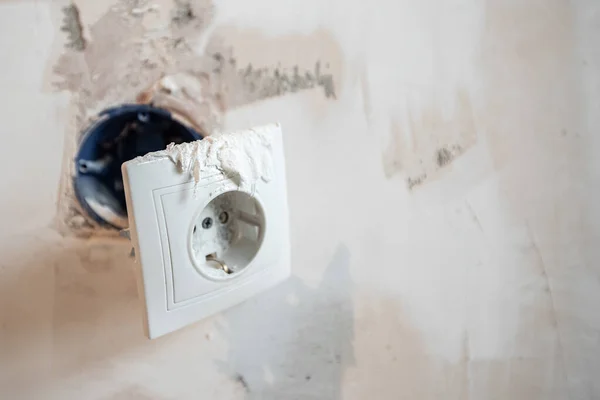 在公寓维修过程中，用裸电线和标志拆开了爆炸壁上的电源插座 — 图库照片