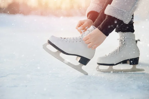 Menina amarra cadarços em patins figura branca para pista de gelo no inverno. Natal feriados conceito — Fotografia de Stock