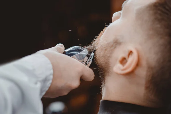 Gros plan de barbe de cisaillement de barbier à l'homme dans le rasoir électrique de salon de coiffure — Photo