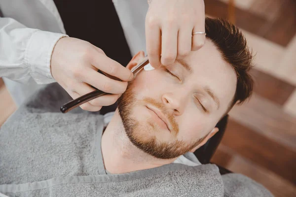 Hombre con barba cliente en peluquería peluquería en afeitarse con maquinilla de afeitar peligrosa — Foto de Stock