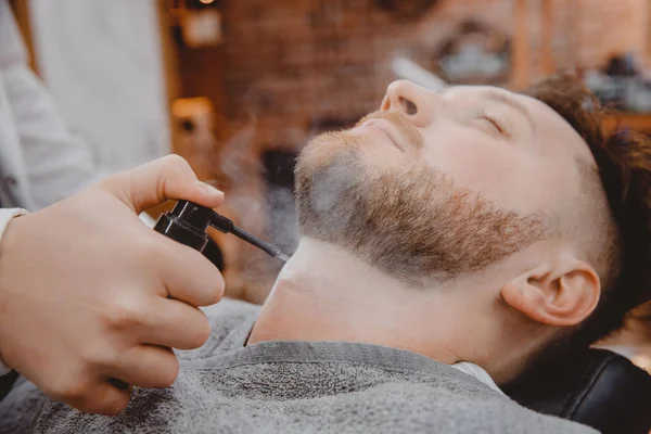 Peluquero trata la piel masculina con talco en polvo y loción para heridas e irritación después de afeitar la barba con afeitadora — Foto de Stock