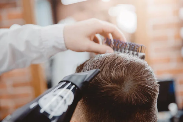 Kapper doet kapsel en styling met droger haar aan man. Concept kapperszaak — Stockfoto