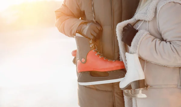 Närbild av skridskor för rinken hålls kille och flicka vänner på bakgrund av vinter och snö — Stockfoto