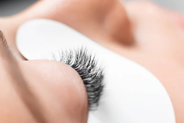 Procédure d'extension des cils dans le salon de beauté spa. Macro Bel oeil avec patch blanc maquillage — Photo