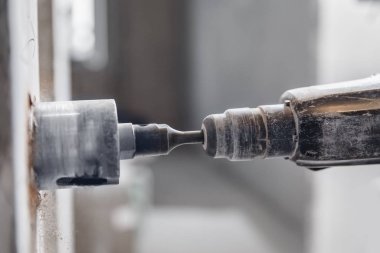 Pnömatik çekiç delici ve elmas kaplama delgisi olan tamirci elektrik kablosu, soket, anahtar için duvarda delik açıyor.