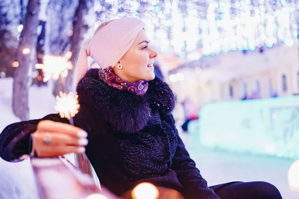 Ritratto giovane bella ragazza sorridente e tenendo sparkler, sfondo illuminazione sera — Foto Stock