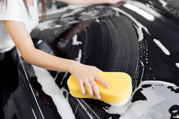 Pozadí ruční houba přes černé auto pro mytí bílé pěny. Horní pohled — Stock fotografie