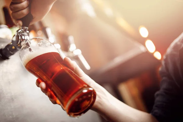 Primo piano mano barman scuro mestiere birra fredda versare in vetro dalla gru in pub — Foto Stock