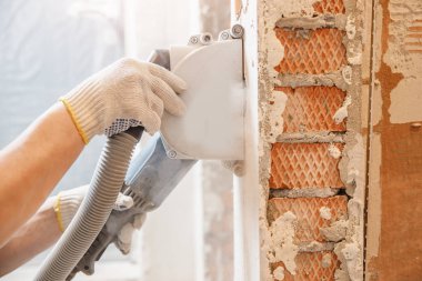 İnşaatçı beton duvarda elektrikli kovalamacayı kesiyor.