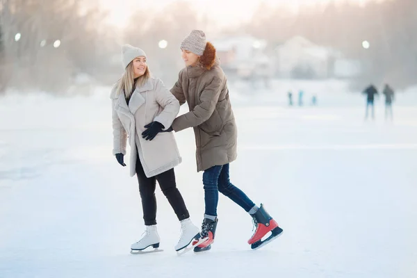 O par de amor jovem feliz mantém mãos, patina na pista, neva no inverno. Conceito férias atividades ao ar livre — Fotografia de Stock