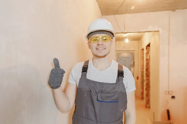 Építő munkás ember boldog biztonsági szemüveg és fehér sisak háttér beton falak. Koncepció képzés speciális iskola a házfestő — Stock Fotó