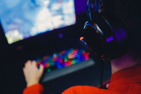 Jugador profesional jugando torneos de juegos en línea ordenador PC con auriculares, fondo rojo y azul borrosa —  Fotos de Stock