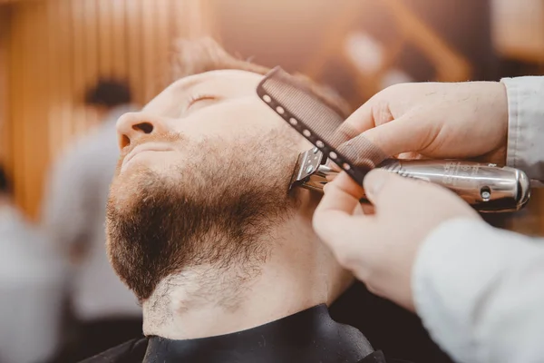 Клиент хипстера, посещающий парикмахерскую, бритая борода, винтажный коричневый тонированный цвет — стоковое фото