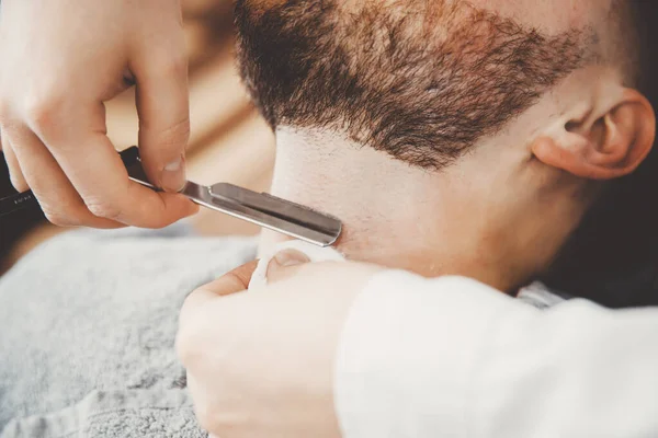 Man met baard klant in kapsalon kapper op scheren met gevaarlijke scheermes — Stockfoto