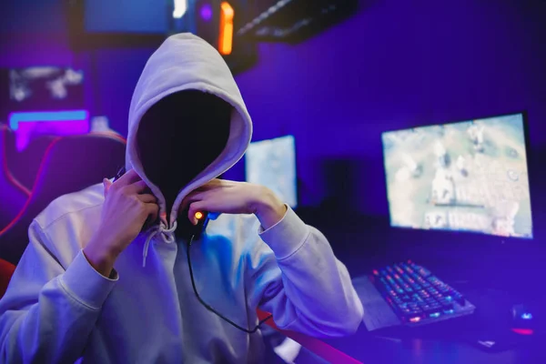 Hombre anónimo en hacker capucha negra está sentado ordenador. Concepto de piratería cibernética —  Fotos de Stock