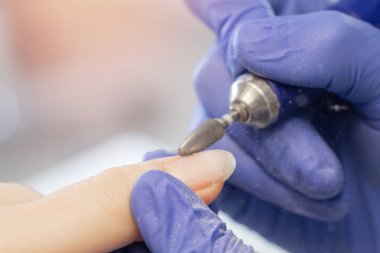 Master removes shellac gel from woman nails salon, manicurist use portable pen shape electric drill manicure