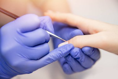 Kapalı kapılar ardında güzel eller çizen kadın güzellik salonunda manikür yaptırıyor.